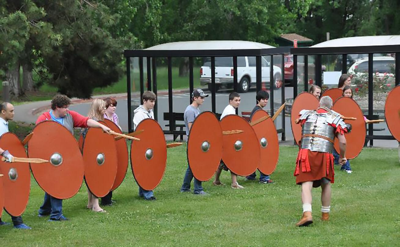Students hold shields outside for Medieval reenactment
